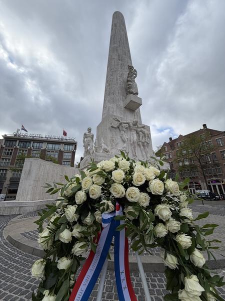 A large white stone obelisk, the National Monument, stands prominently under a cloudy sky in Dam, Centrum, Amsterdam